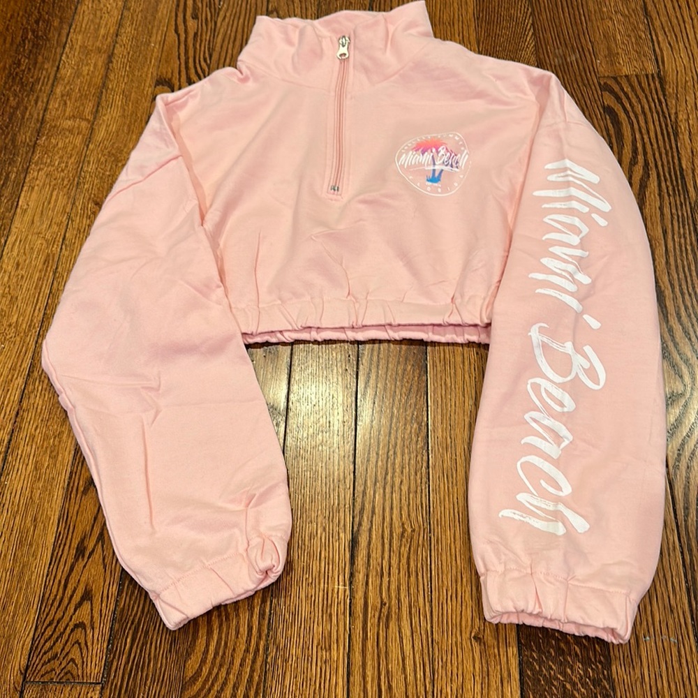 Pink cropped turtleneck sweatshirt. Writing on it says Miami Beach